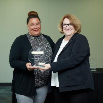 two female faculty holding an award between them